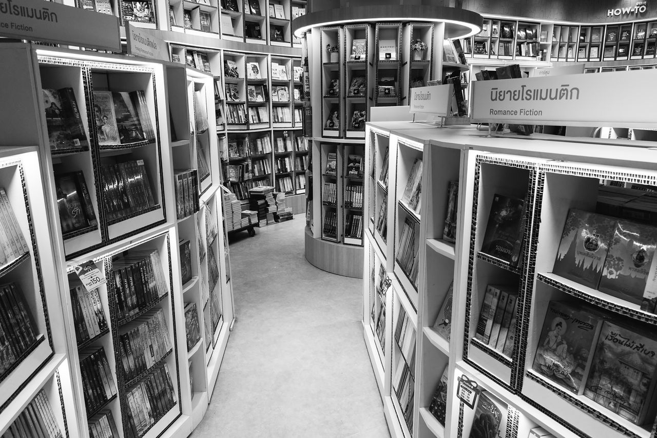 Monochrome view of a bookstore's interior with various bookshelves and romance fiction section.